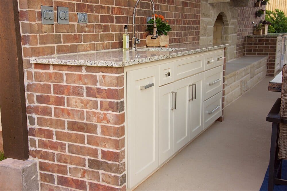 Outdoor Kitchen Featuring Sink in Counter and A Brick Backsplash