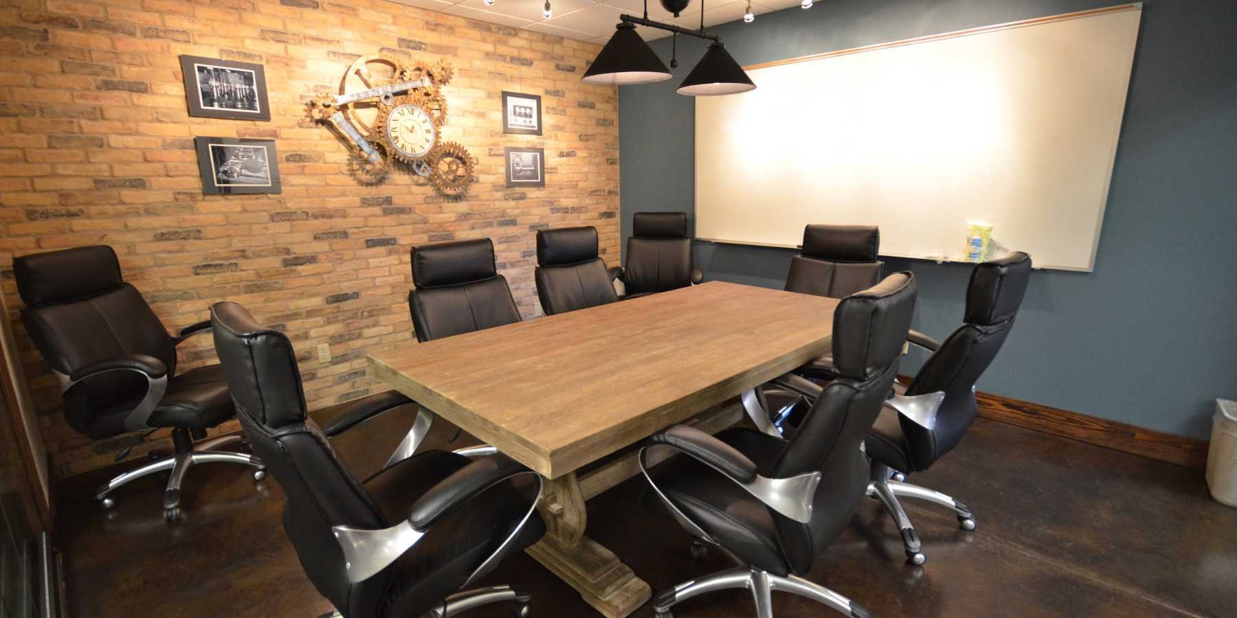 Meeting Table with Black Rolling Office Chairs and Large White Board Banner