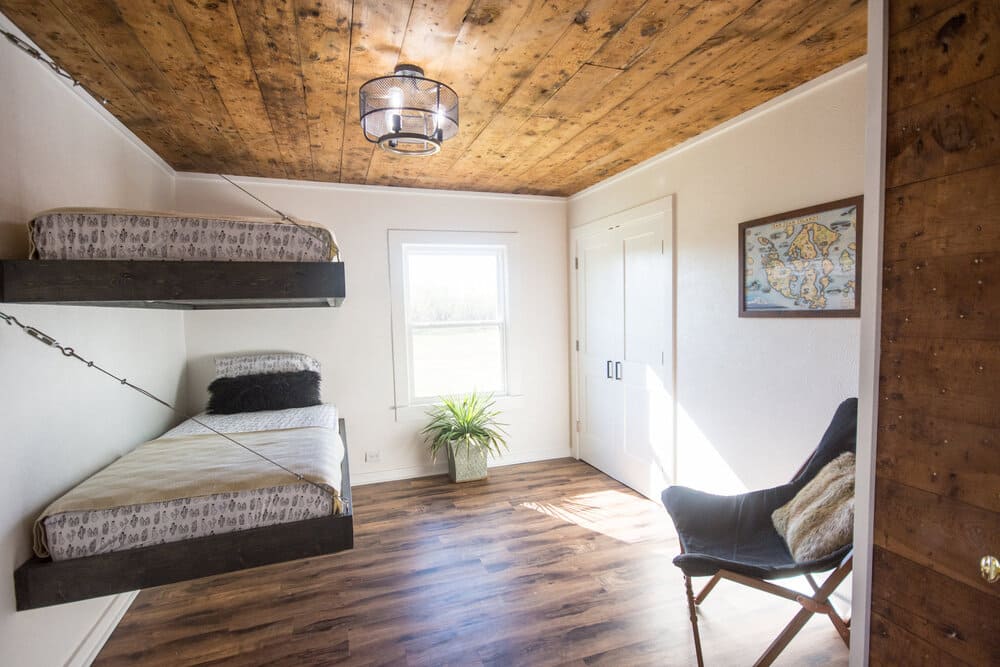 A room with two bunk beds and a chair.