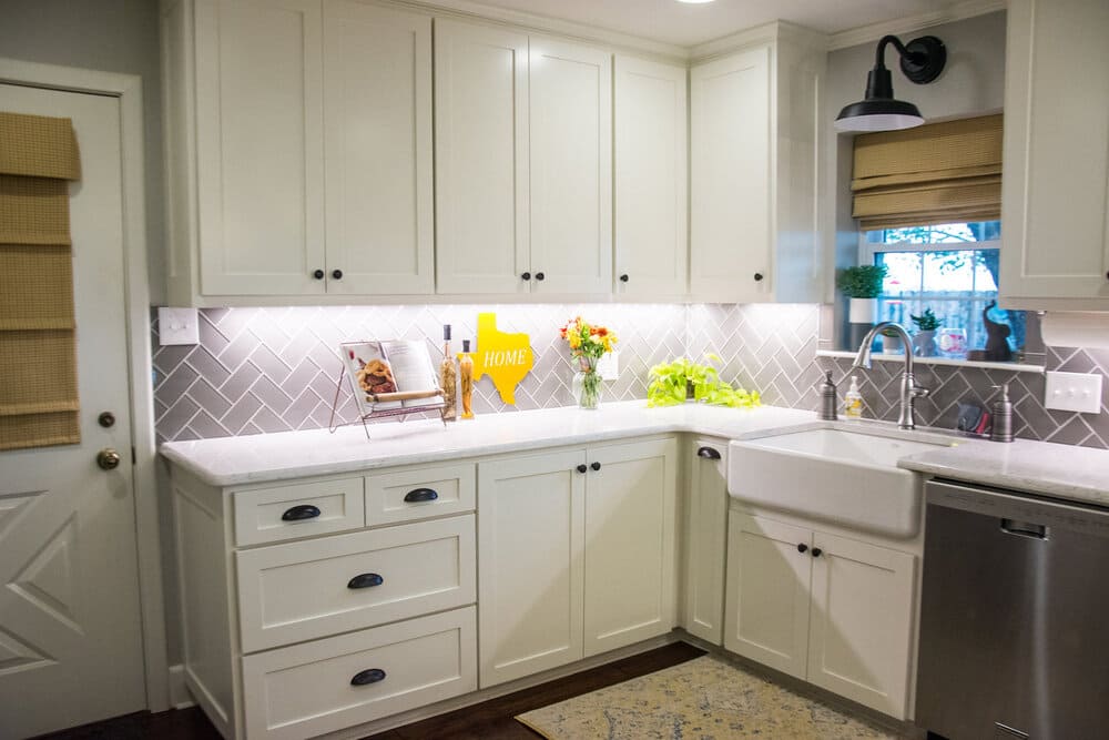 Corner of White Rural Kitchen with Many Cabinets and Stainless Steel Faucet
