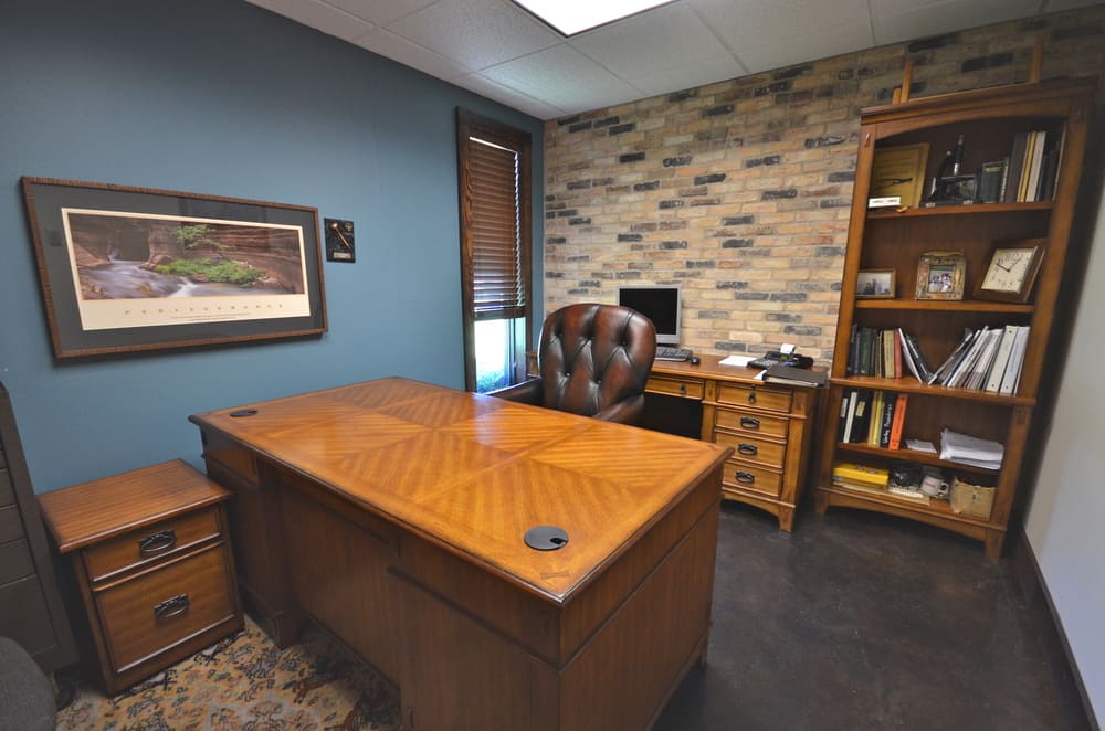 Commercial Office Space with Large Wooden Desk and Blue Wall and Multicolor Brick Wall