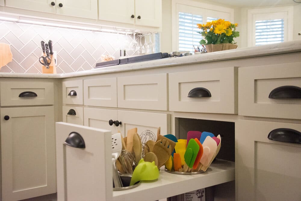 White Cabinets Featuring a Pull Out Storage Area with Many Cooking Utensils